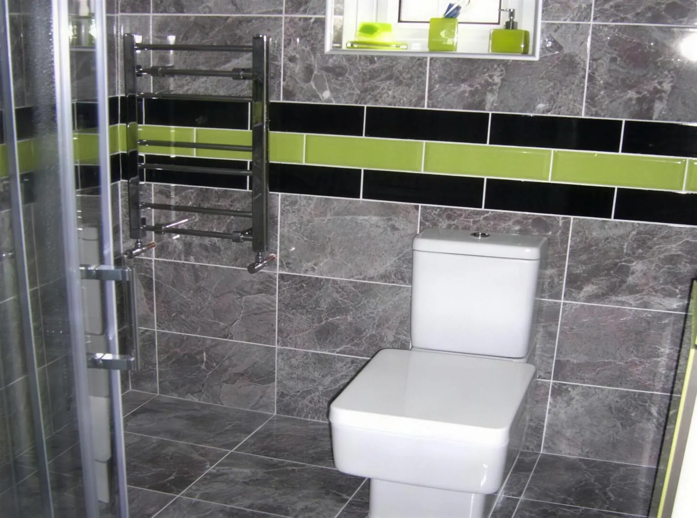 Tiled toilet and shower area with a contrasting tile border
