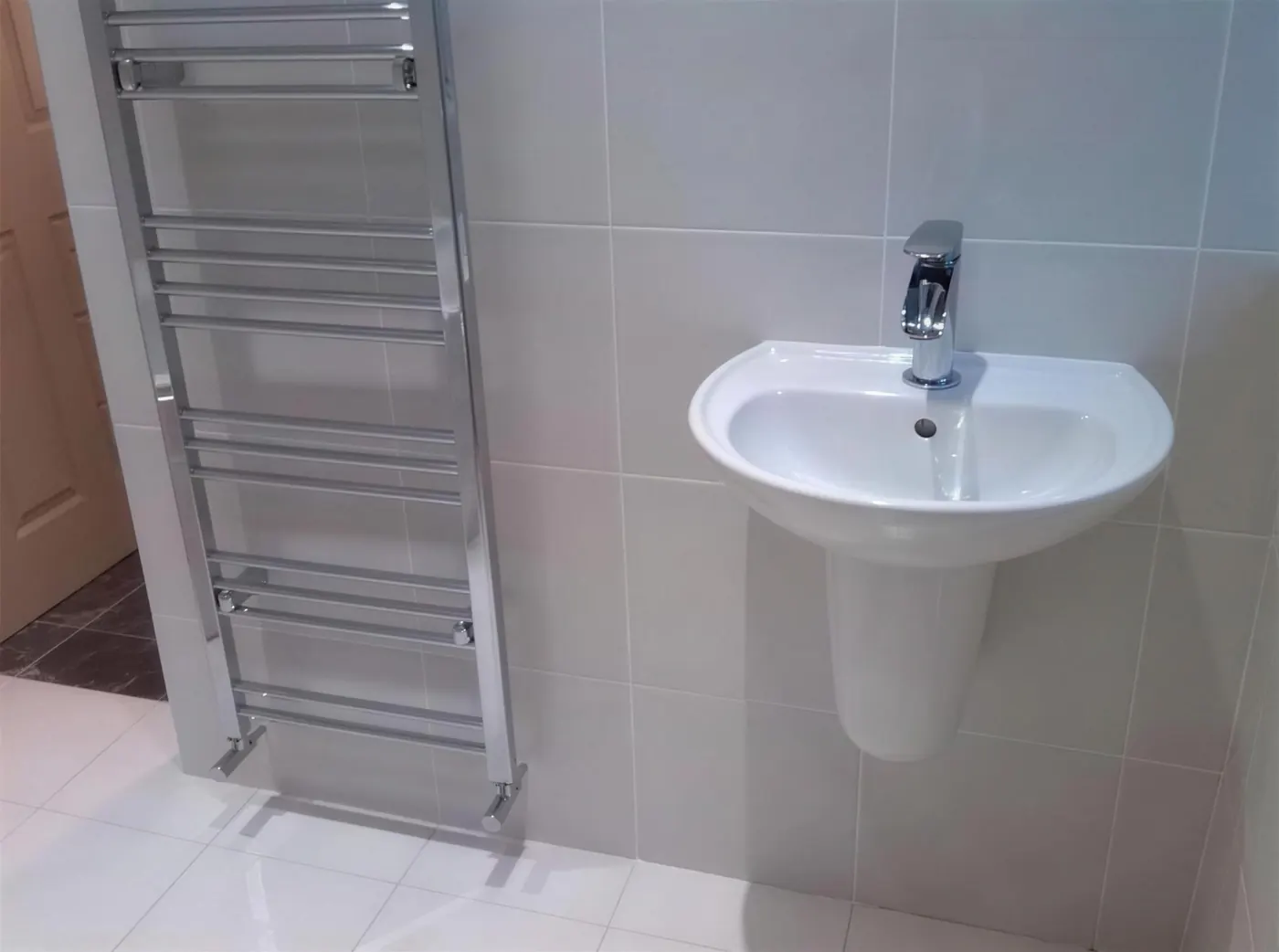 Tiled bathroom wall with basin and heated towel rail