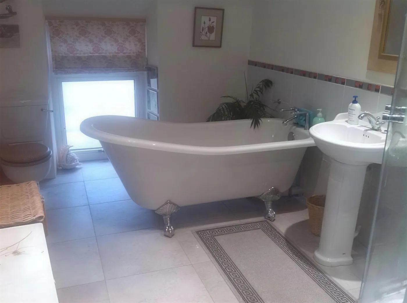Fitted bathroom with a roll top bath and tiled floor in a period property