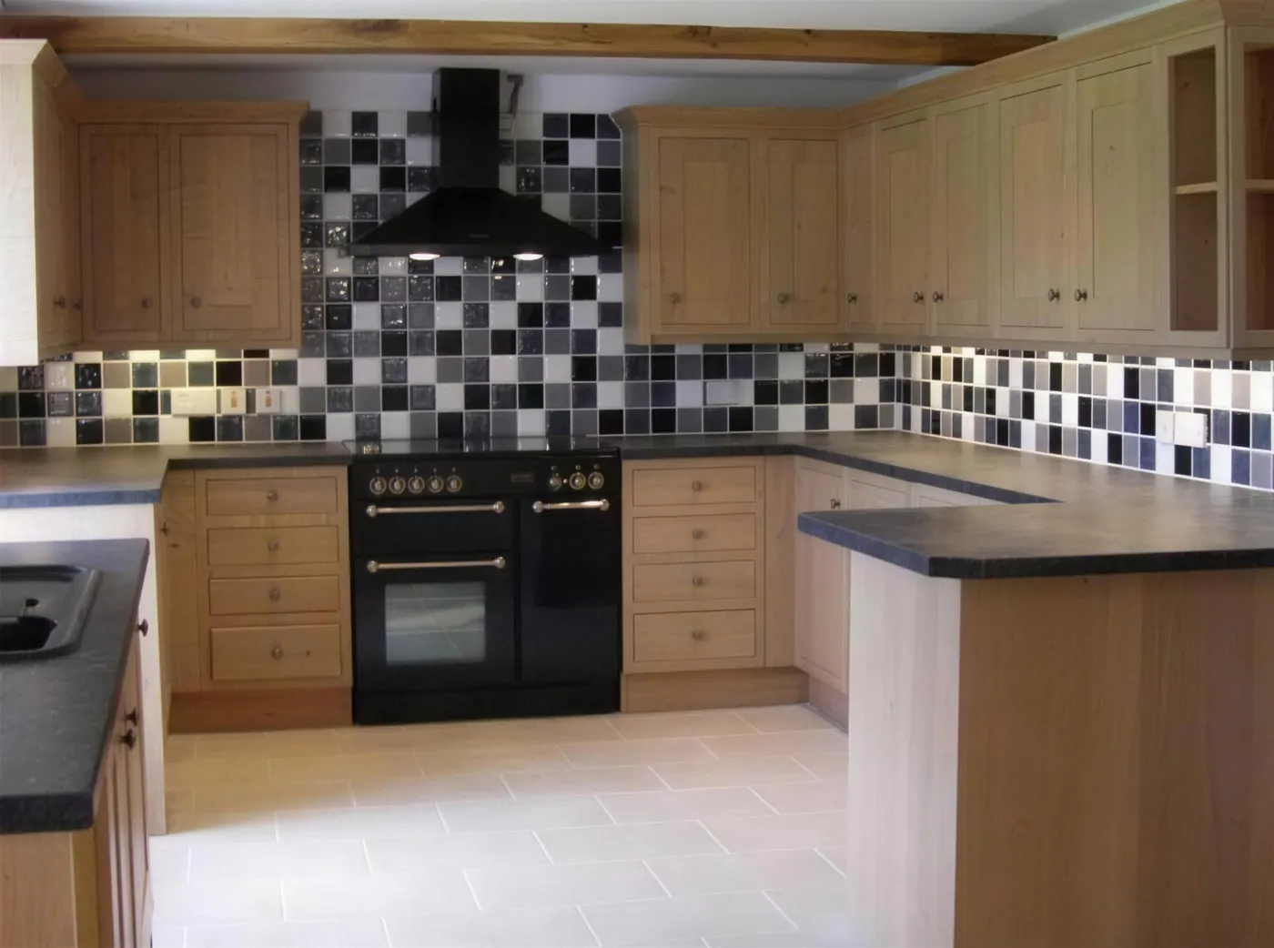 Fitted kitchen with oak units, range cooker and a mosaic tiled splashback