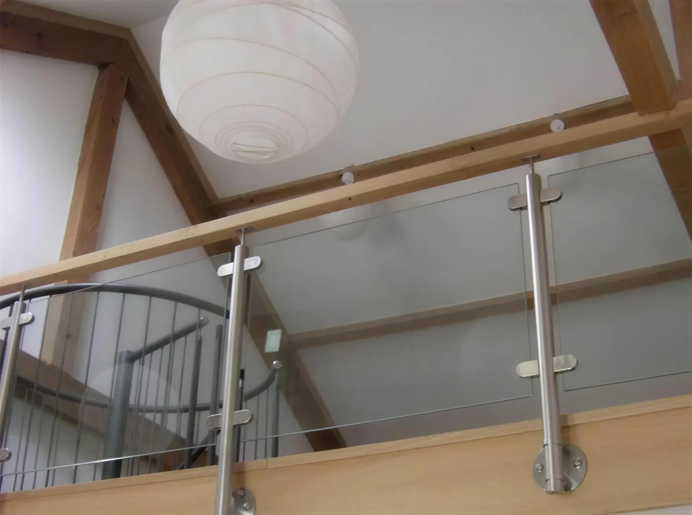 Glass and steel balustrade on a galleried landing under oak roof trusses