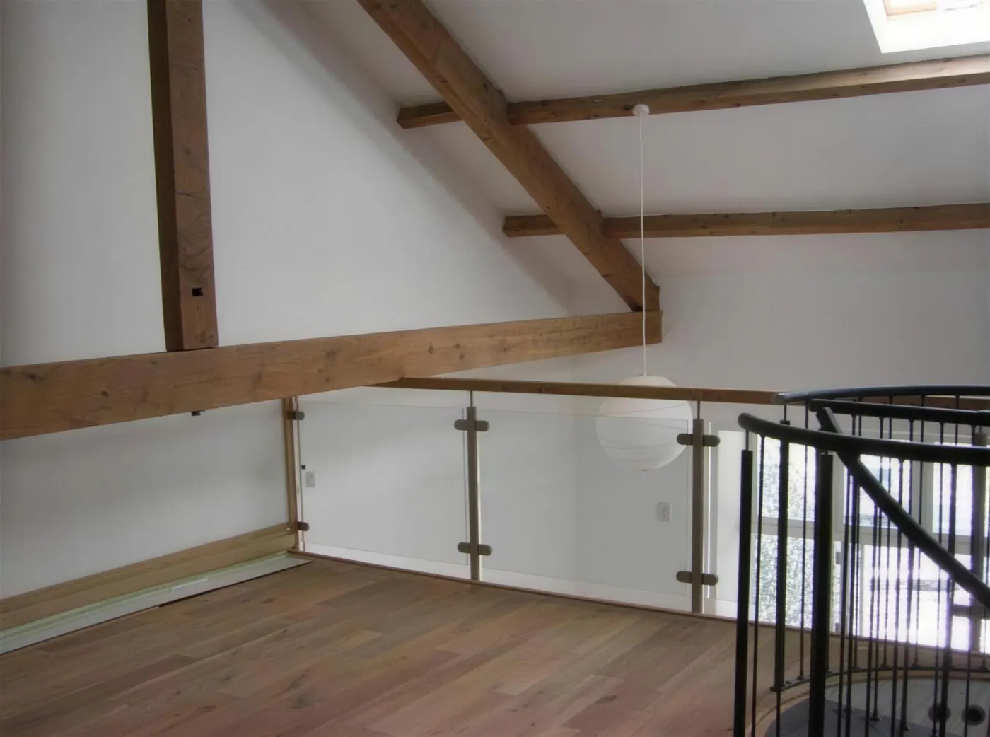 Converted loft space with exposed oak trusses and a glass balustrade
