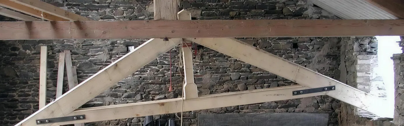 Oak roof truss set against a slate stone wall in a barn conversion
